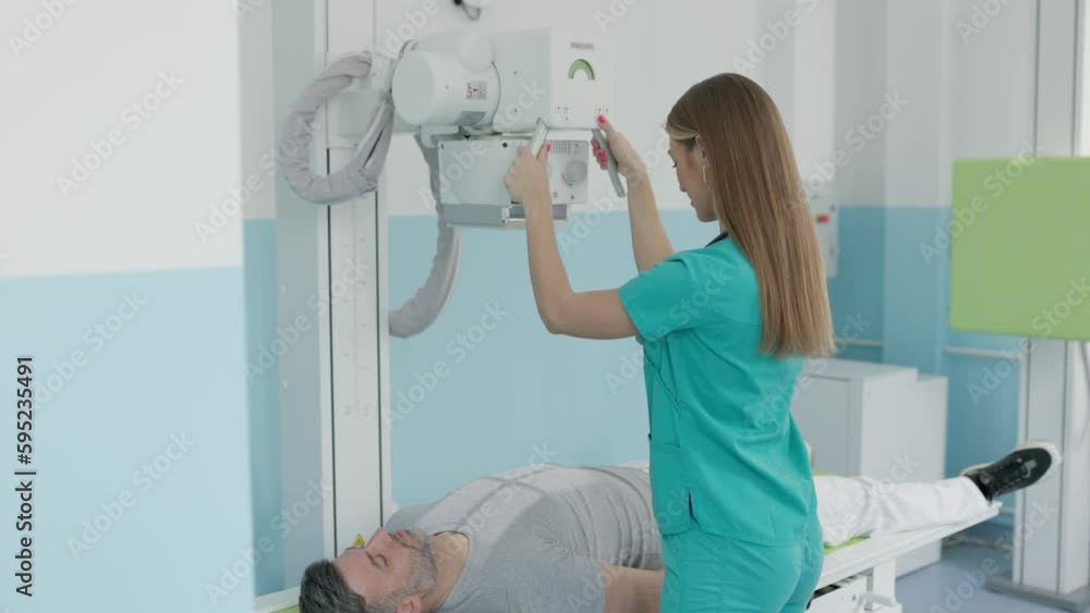 Female doctor sets up the machine to xray over patient. Radiologist