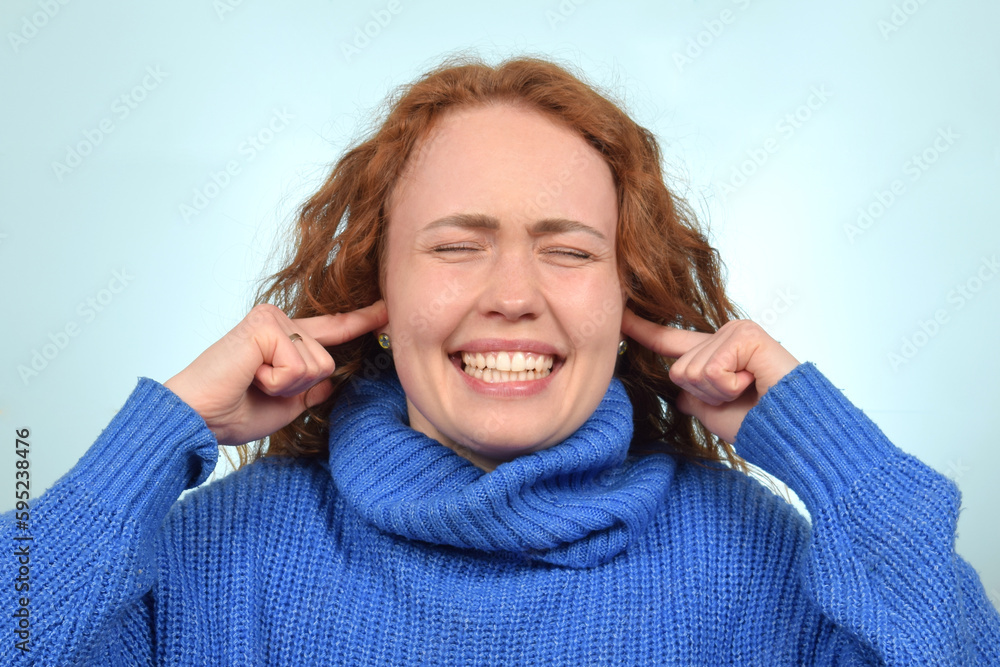 red-haired cute woman covered her ears with her fingers and screams red-haired cute woman covered her ears with her fingers and screams