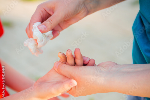 The woman's hands wipe the boy's child's hand with a napkin. Disinfection while walking.
