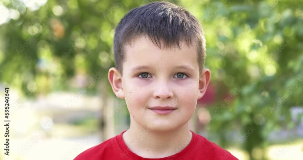 Closeup portrait of little boy standing in sunny park outdoors Closeup portrait of little boy standing in sunny park outdoors