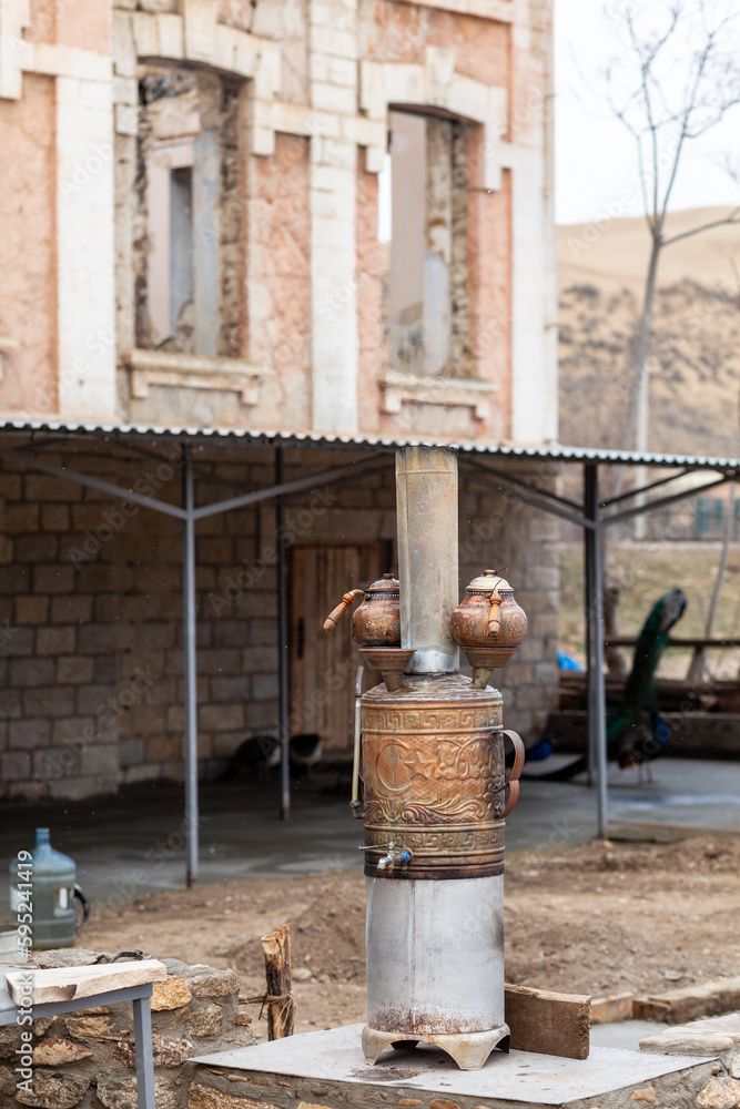 An old Turkish wood-burning samovar with two copper kettles near a cafe for vacationing tourists. An old Turkish wood-burning samovar with two copper kettles near a cafe for vacationing tourists.