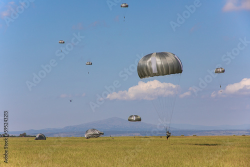 Un grupo de soldados paracaidistas toman tierra en el campo durante unas maniobras. photo