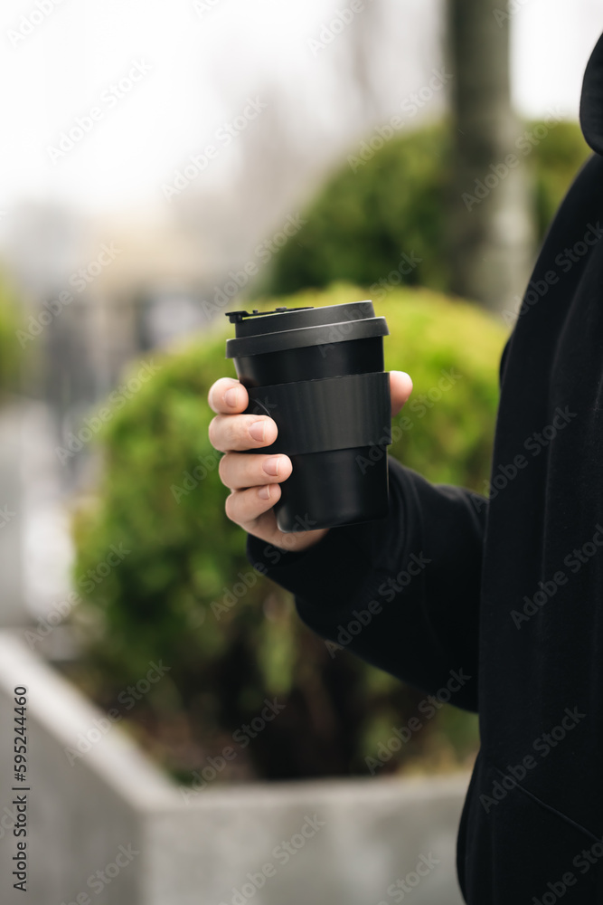 Reusable stylish bamboo black cup in the hands of a man, close-up, Eco friendly sustainable handy bamboo cup zero waste, no plastic concept. Reusable stylish bamboo black cup in the hands of a man, close-up, Eco friendly sustainable handy bamboo cup zero waste, no plastic concept.
