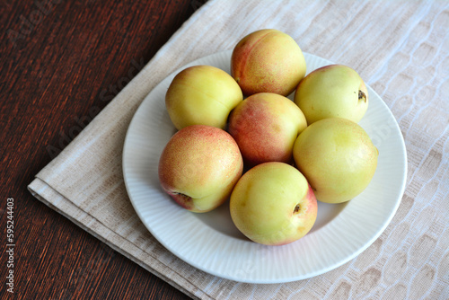 A plate of yellow plums on a table with a pastel tablecloth  close-up