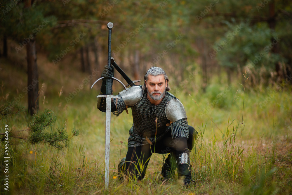an old warrior in chain mail with a sword is looking for prey in the forest.