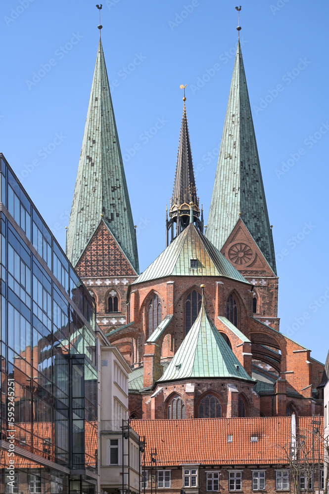 Lubeck Marienkirche or St. Mary Church, historic medieval basilica built in north German Brick Gothic with two monumental towers, seen from the west with reflections in a modern glass facade