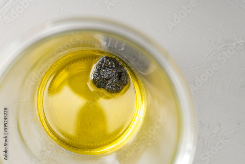 Fresh black truffle lying for several days in olive oil in a glass jar for homemade truffle oil, high angle view from above, copy space, selected focus