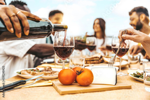 Fotografia Happy friends drinking red wine sitting at winery restaurant balcony -Group of p