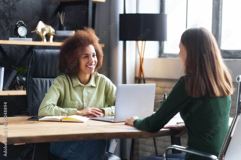 Friendly interview between African American businesswoman hr director and caucasian job candidate. Recruitment manager talking, hiring for job female sitting in office