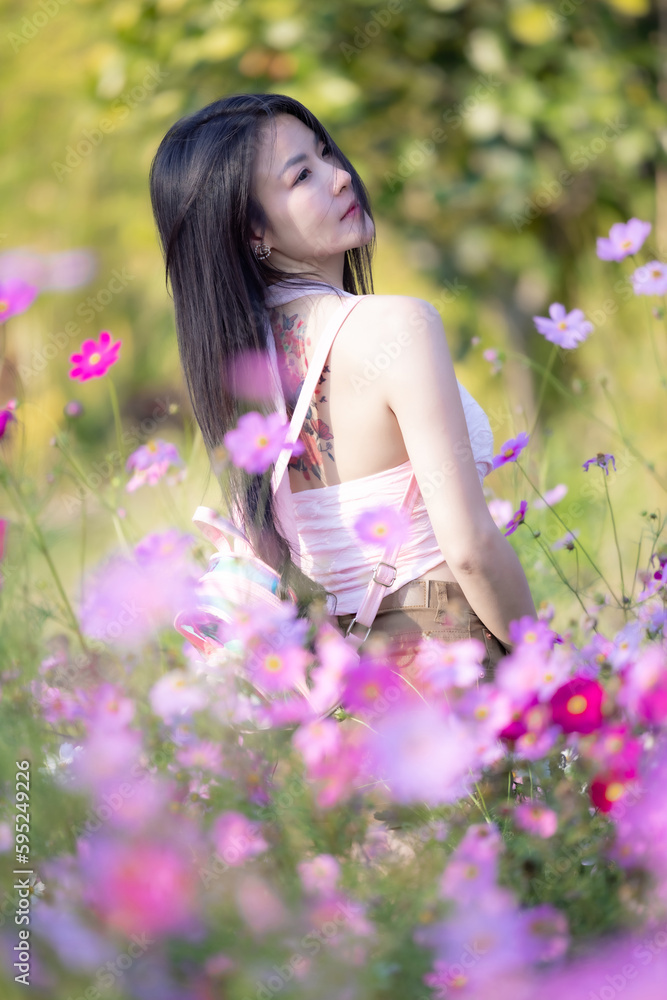 Beautiful woman happy traveler walking in the flowers garden. Young woman smile and relaxing with happy around outdoor garden. Woman's hand touching and enjoying beauty cosmos flowers.Travel concept. Beautiful woman happy traveler walking in the flowers garden. Young woman smile and relaxing with happy around outdoor garden. Woman's hand touching and enjoying beauty cosmos flowers.Travel concept.