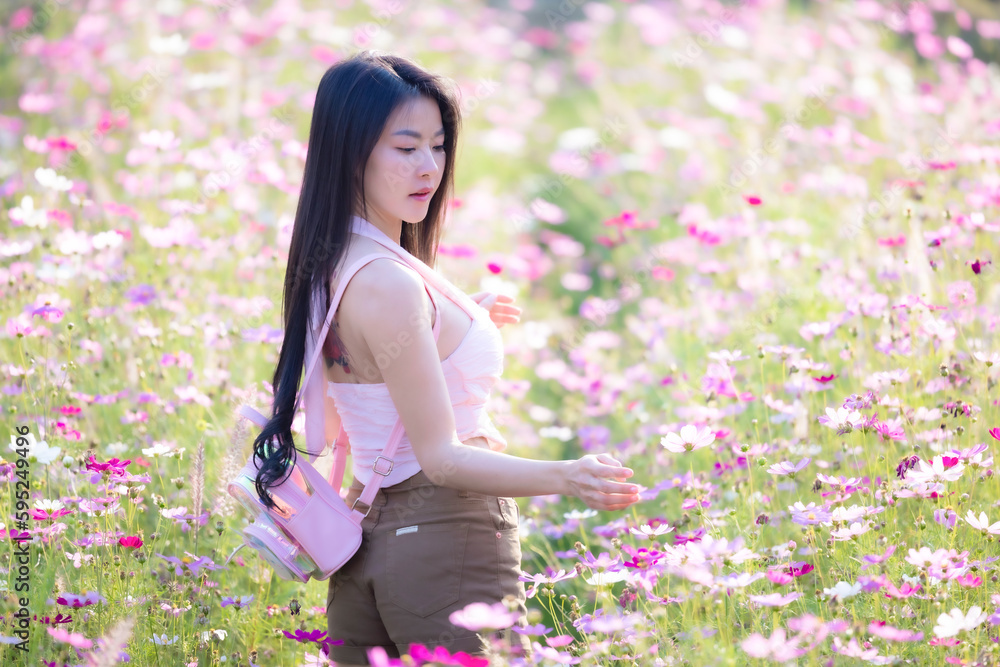 Beautiful woman happy traveler walking in the flowers garden. Young woman smile and relaxing with happy around outdoor garden. Woman's hand touching and enjoying beauty cosmos flowers.Travel concept. Beautiful woman happy traveler walking in the flowers garden. Young woman smile and relaxing with happy around outdoor garden. Woman's hand touching and enjoying beauty cosmos flowers.Travel concept.