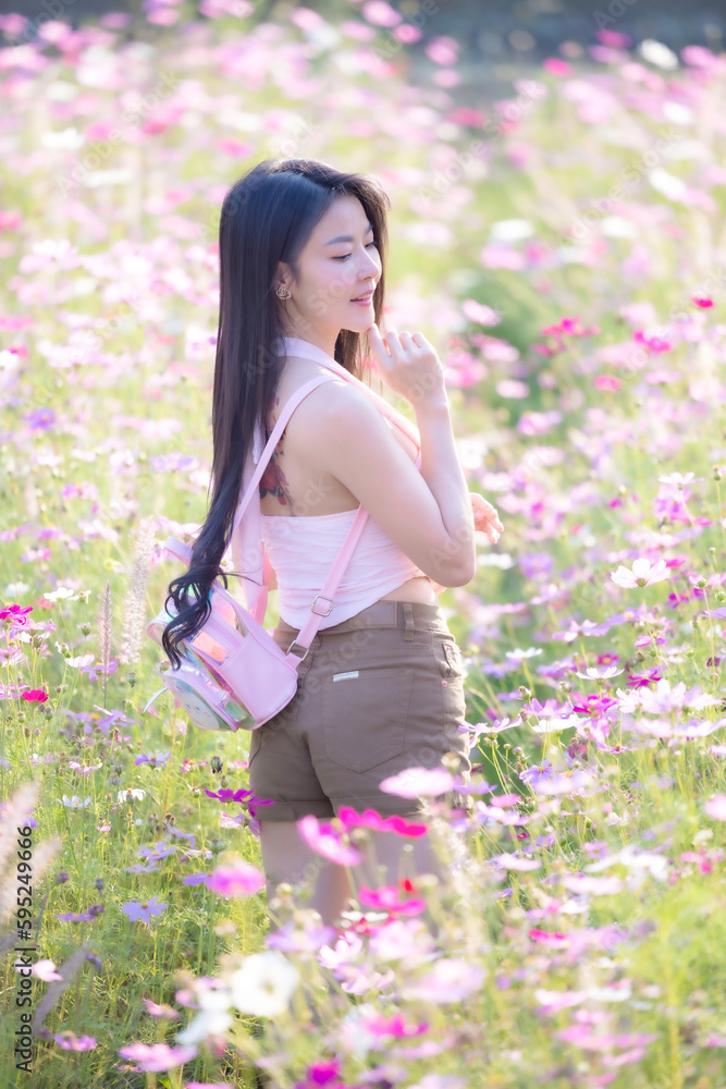 Beautiful woman happy traveler walking in the flowers garden. Young woman smile and relaxing with happy around outdoor garden. Woman's hand touching and enjoying beauty cosmos flowers.Travel concept. Beautiful woman happy traveler walking in the flowers garden. Young woman smile and relaxing with happy around outdoor garden. Woman's hand touching and enjoying beauty cosmos flowers.Travel concept.