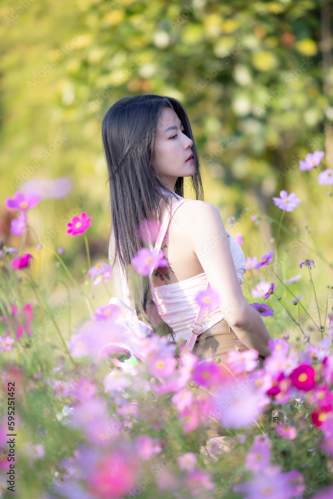 Beautiful woman happy traveler walking in the flowers garden. Young woman smile and relaxing with happy around outdoor garden. Woman's hand touching and enjoying beauty cosmos flowers.Travel concept. Beautiful woman happy traveler walking in the flowers garden. Young woman smile and relaxing with happy around outdoor garden. Woman's hand touching and enjoying beauty cosmos flowers.Travel concept.