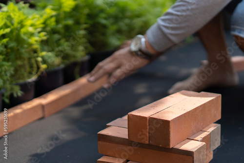 Selective focus. Gardener s hands carefully place and arrange the bricks in the mini garden.
