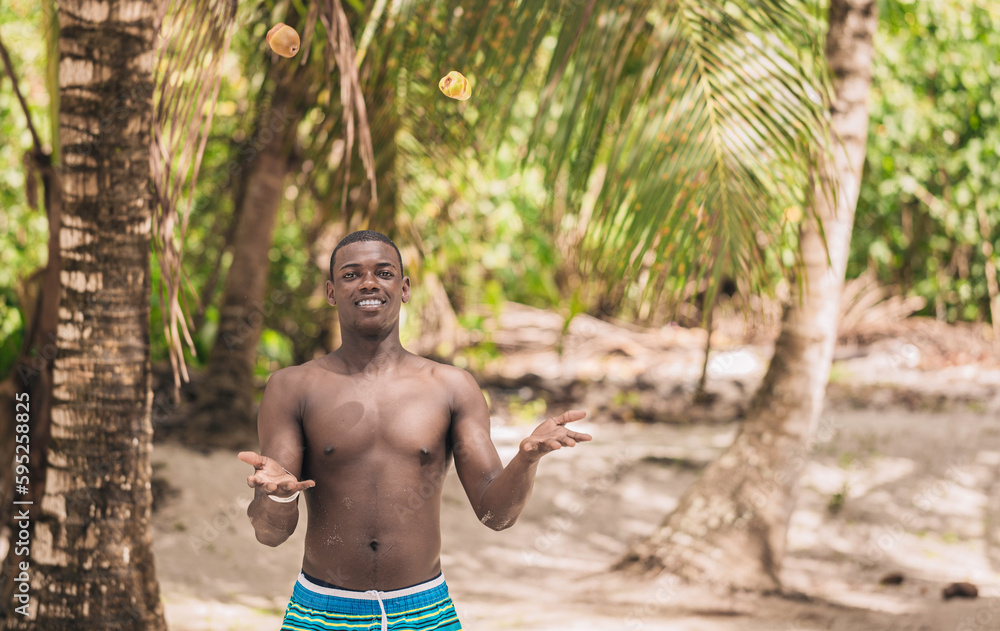 Smiling black man juggling fruit on the beach Smiling black man juggling fruit on the beach