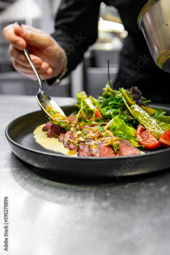 Fototapeta Naklejka Na Ścianę i Meble -  chef hand cooking Roast beef salad with vegetables on restaurant kitchen
