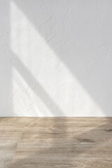 Sun light shadows on white textured wall and beige wooden floor, blank design template for home room interior or product stand mock up, business brand advertisement background, copy space