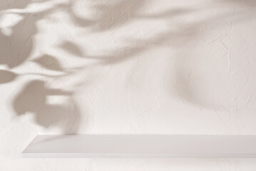 Empty shelf on beige textured plaster wall background with aesthetic floral sun light shadows, product placement or podium design template for business branding advertisement, mock up with copy space