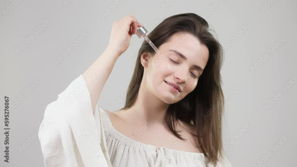 Woman applying face serum with moisturizing dropper, morning skin care. Beautiful woman uses face oil with dropper and moisturizes her cheeks, health and face care concept Woman applying face serum with moisturizing dropper, morning skin care. Beautiful woman uses face oil with dropper and moisturizes her cheeks, health and face care concept