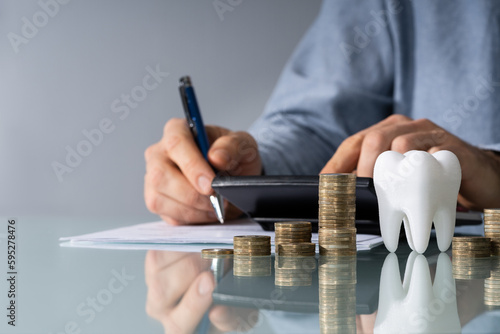 Tooth In Front Of Businessperson Calculating Bill
