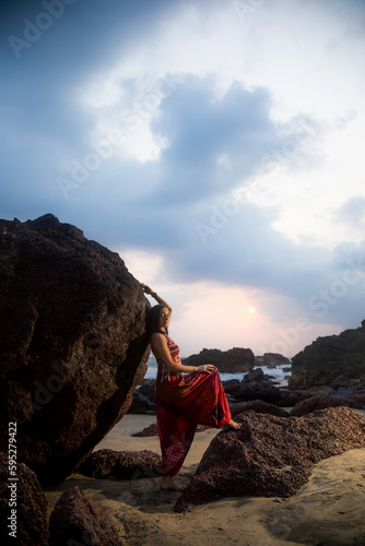 Young beautiful healthy woman making meditation on the rocks, sunset on the sea. Arambol, Goa, India.