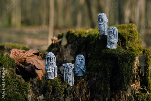 Antique ritual stone idols on tree stump close up, abstract natural forest background. gods totems in traditional Slavic folk style. folklore Ethnic handicraft. Attribute of pagan religious rites. photo