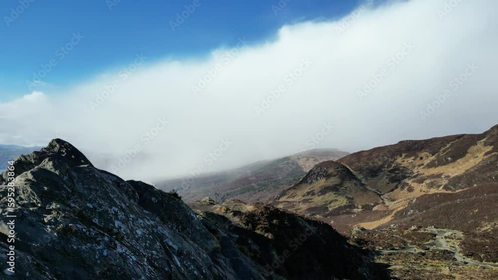 Aerial of low clouds over the calm river and mountains under the blue sky Aerial of low clouds over the calm river and mountains under the blue sky