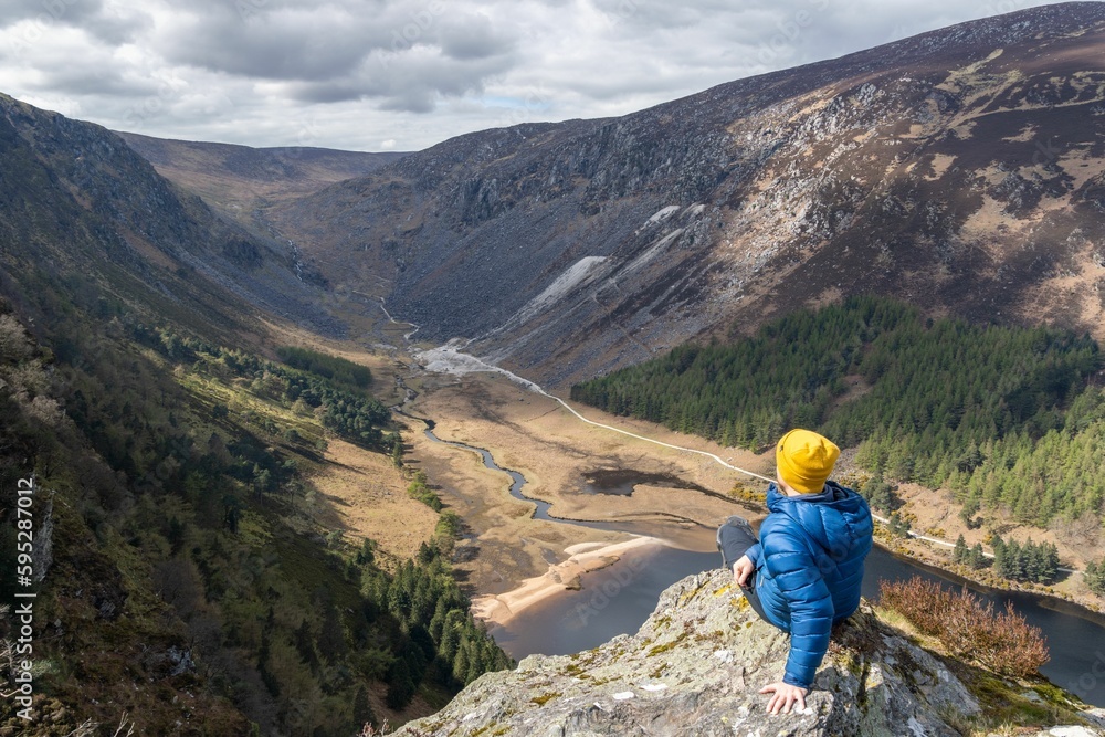 High angle shot of a hiker enjoying the view from the Spink Glendalough Viewpoint in Ireland High angle shot of a hiker enjoying the view from the Spink Glendalough Viewpoint in Ireland