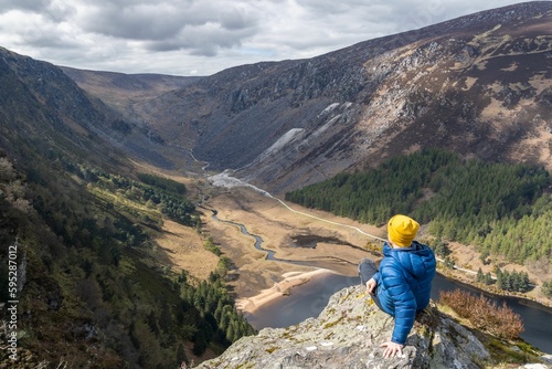 High angle shot of a hiker enjoying the view from the Spink Glendalough Viewpoint in Ireland