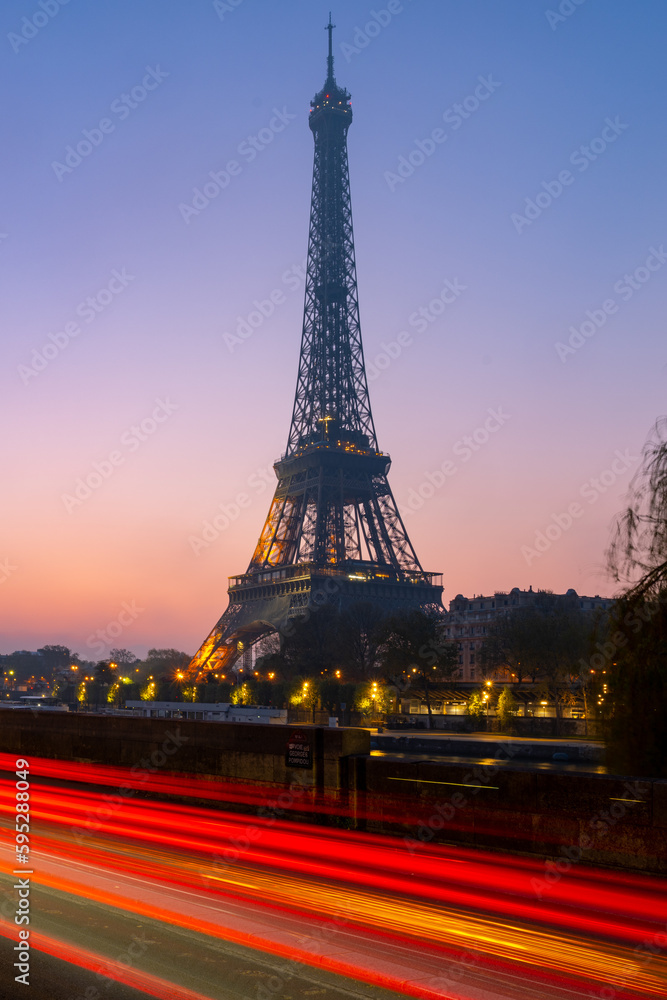 Eiffel Tower, French: Tour Eiffel, silhouette at dawn with blurred long exposure red traffic lights. Paris, France