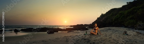 Young beautiful healthy woman making meditation on the beach, sunset on the sea. Arambol, Goa, India.