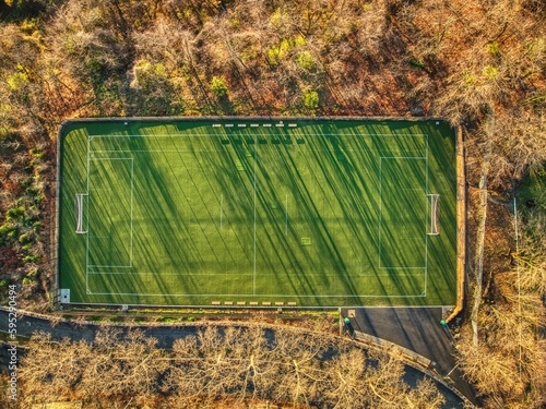 Aerial top view of an empty soccer field surrounded by lush green trees in a forest setting photo