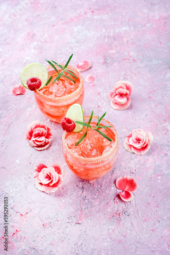 Klassischer Rosa Daiquiri mit Rum, Orangen Likör und Limetten Saft serviert als Valentinstag Geschenk in zwei Gläsern und dekoriert mit Rosen und Himbeeren photo