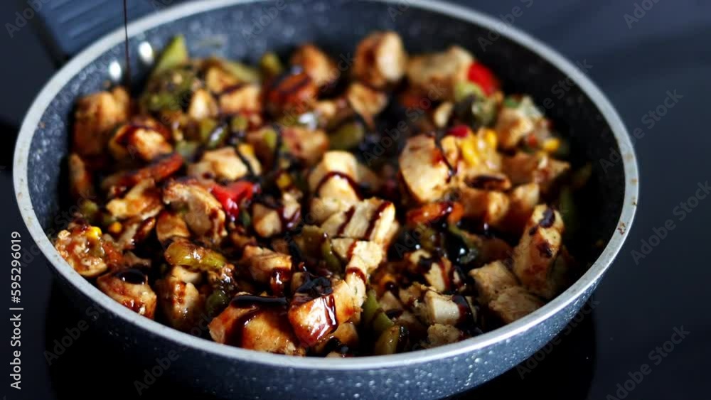 The chef pours sauce on vegetables with meat that is stewed in a pan. Cooking in a restaurant's kitchen The chef pours sauce on vegetables with meat that is stewed in a pan. Cooking in a restaurant's kitchen