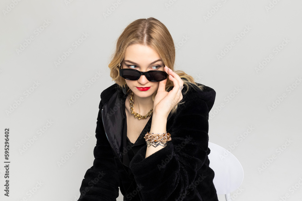 Young Curly blonde girl elegantly dressed, with a bright red lipstick on the lips and a black sunglasses. expensive clothes, style and fashion concept. Young Curly blonde girl elegantly dressed, with a bright red lipstick on the lips and a black sunglasses. expensive clothes, style and fashion concept.