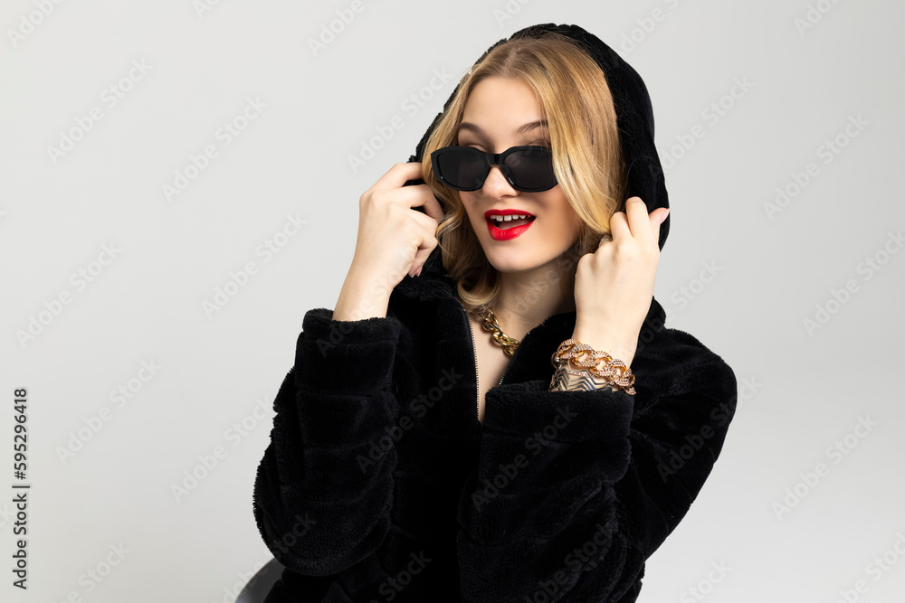 Young Curly blonde girl elegantly dressed, with a bright red lipstick on the lips and a black sunglasses. expensive clothes, style and fashion concept. Young Curly blonde girl elegantly dressed, with a bright red lipstick on the lips and a black sunglasses. expensive clothes, style and fashion concept.