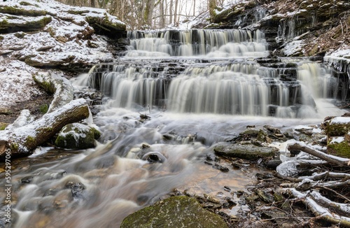 Striking winter scene features a majestic waterfall surrounded by towering tree branches