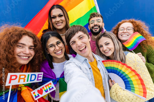 Diverse LGTBQ young people with rainbow flags celebrating gay pride parade festival. Cheerful gay and lesbian community friends demonstrating for LGTB equal rights. Transgenders and homosexual people.