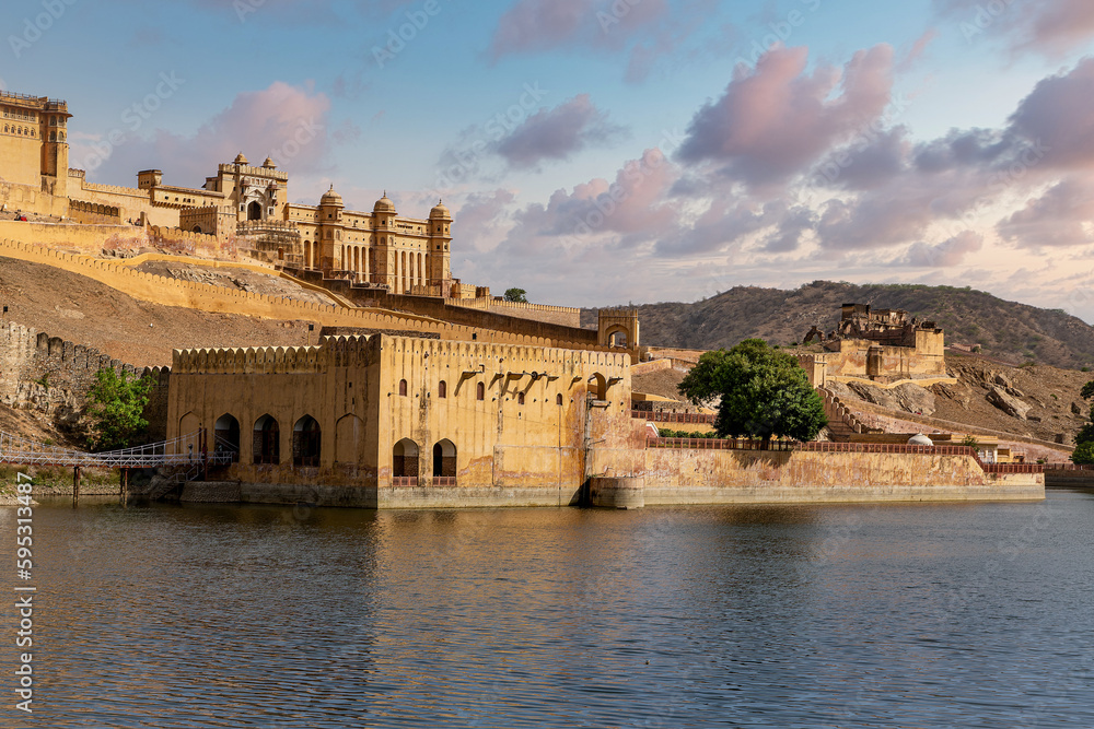 Amber Fort illuminated by warm light of the rising sun and reflected in the lake. Famous Rajasthan landmark