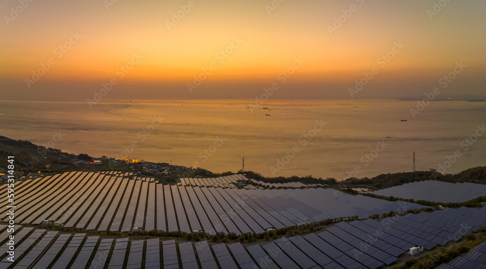 Sunset glow reflects off solar panels at coastal energy farm