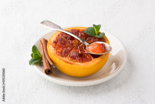Fotografie Baked grapefruit with brown sugar and cinnamon garnished with mint on a light gray background