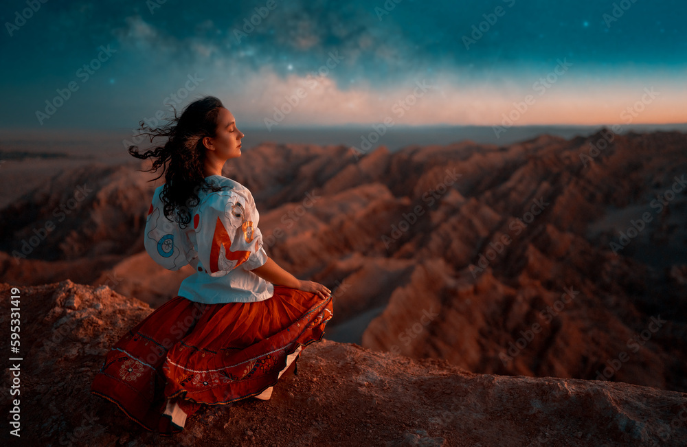 young woman sitting in viewpoint meditating breathing the warm breeze of the desert in San Pedro de Atacama