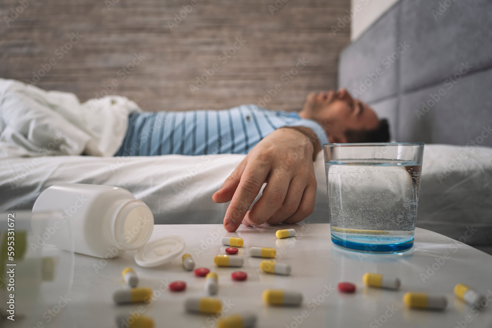 a man sleeps on a bed . table with pills and a glass of water. Sleeping pills for a good sleep. Man sleeping - pills on bed table. drug overdose. a lethal dose of the drug, a man sleeps on a bed . table with pills and a glass of water. Sleeping pills for a good sleep. Man sleeping - pills on bed table. drug overdose. a lethal dose of the drug,
