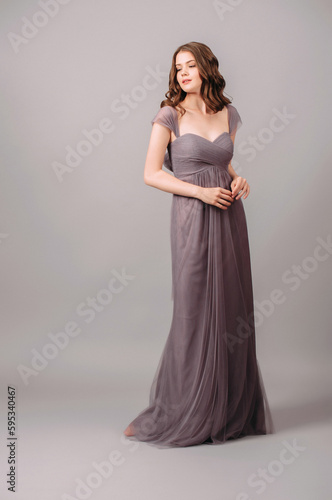 Elegant purple sleeveless transformer dress with high waist. Beautiful lilac chiffon gown with twisted knots. Studio sensual portrait of a young brunette woman. Summer fancy female look.