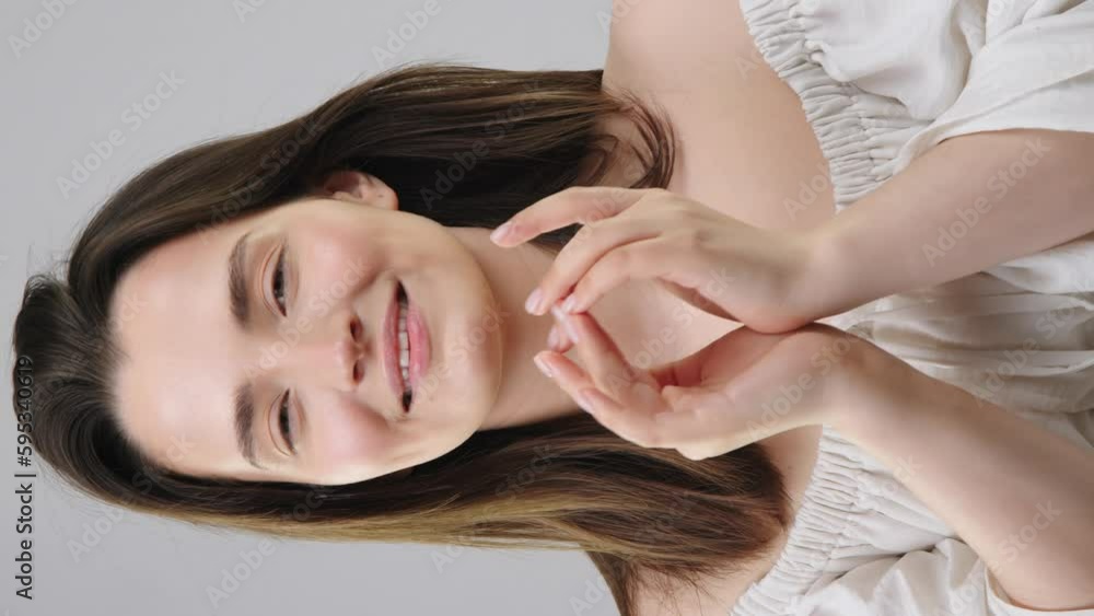 Beautiful european skincare model applying eye cream while smiling broadly at the camera in the background. Eye cream with shot application for face care advertising Beautiful european skincare model applying eye cream while smiling broadly at the camera in the background. Eye cream with shot application for face care advertising
