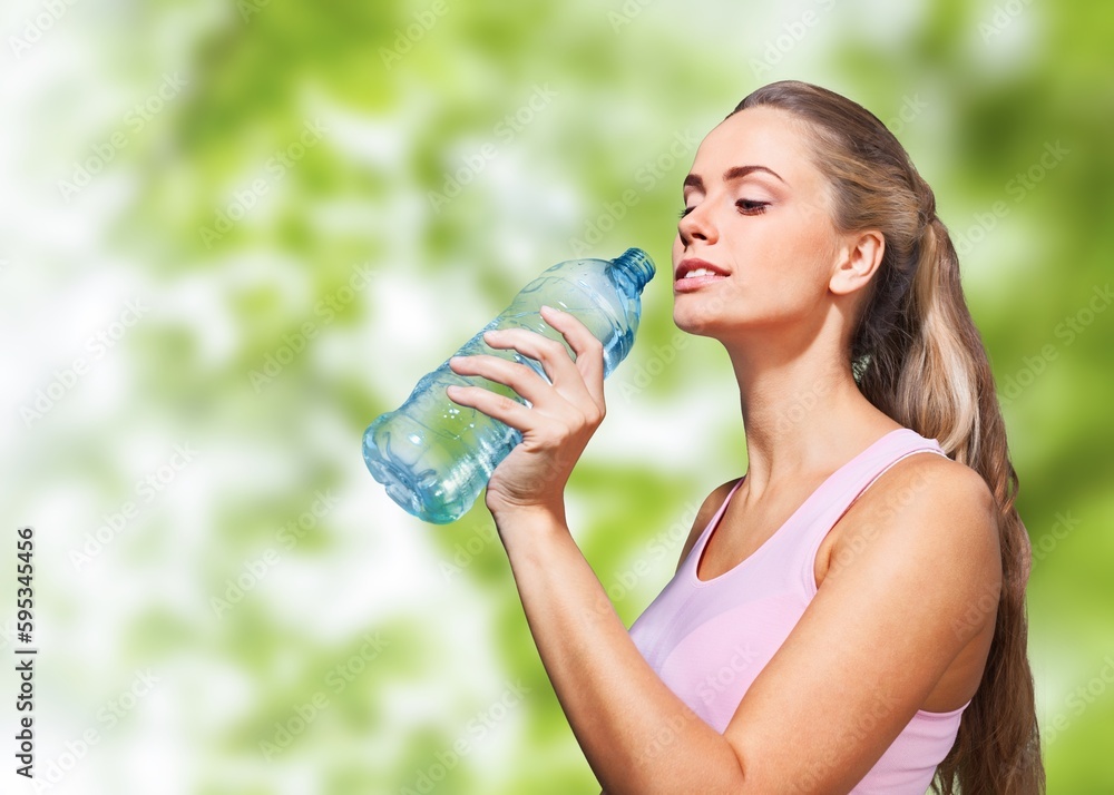 Happy slim young woman drinking clean water after workout Happy slim young woman drinking clean water after workout