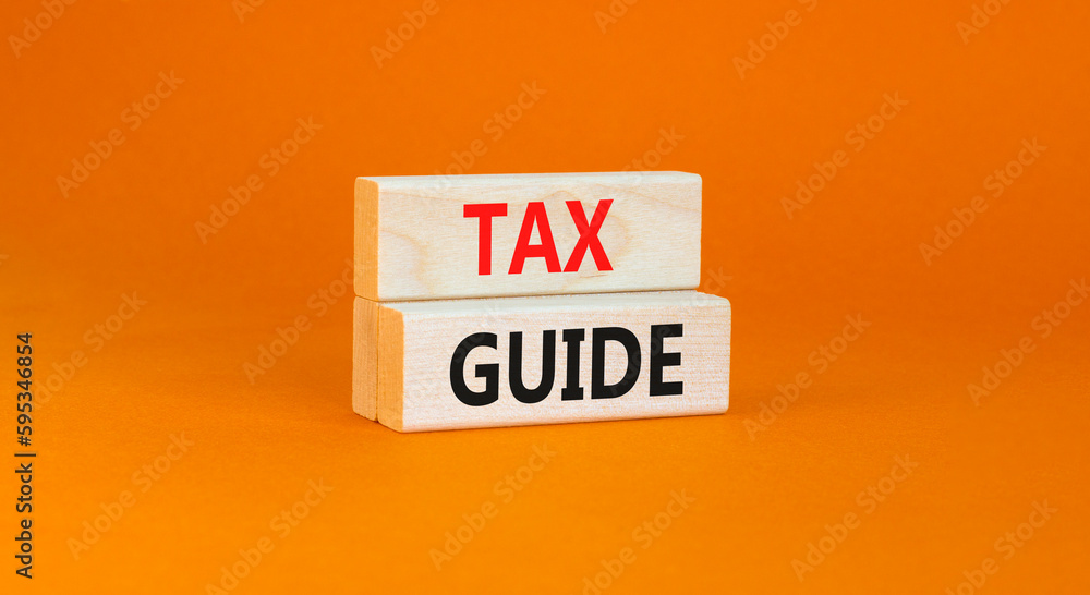 Tax guide symbol. Concept words Tax guide on beautiful wooden block. Beautiful orange table orange background. Business and Tax guide concept. Copy space. Tax guide symbol. Concept words Tax guide on beautiful wooden block. Beautiful orange table orange background. Business and Tax guide concept. Copy space.