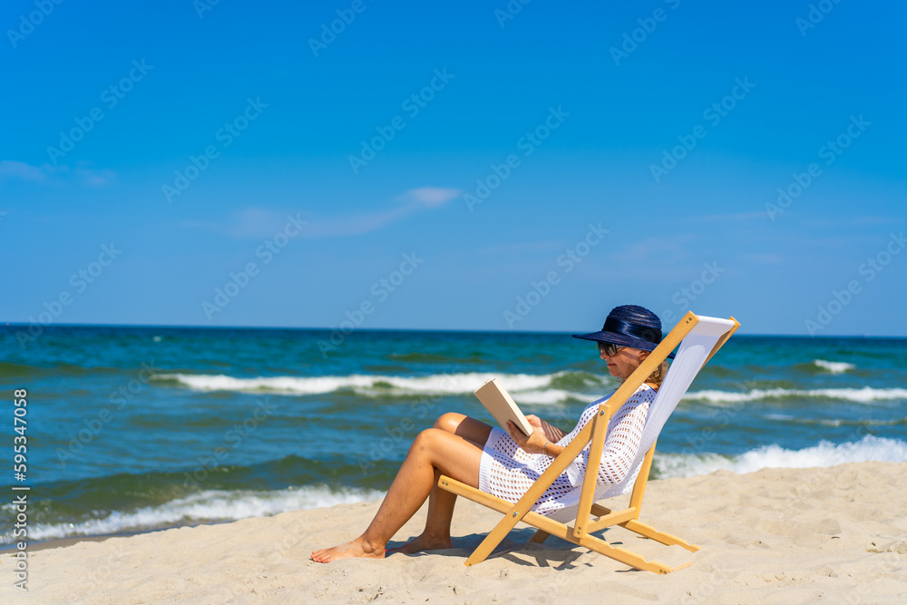 Woman relaxing on beach reading book sitting on sunbed
Woman relaxing on beach reading book sitting on sunbed