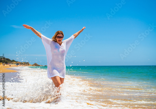 Beautiful woman walking on sunny beach 