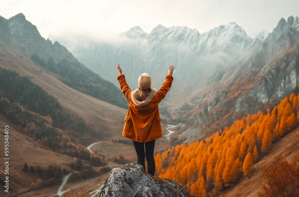 Obraz premium Beautiful mountains in fog and a standing young woman with arms raised